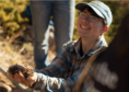 Lior Gross kneeling down, smiling, holding some soil. 